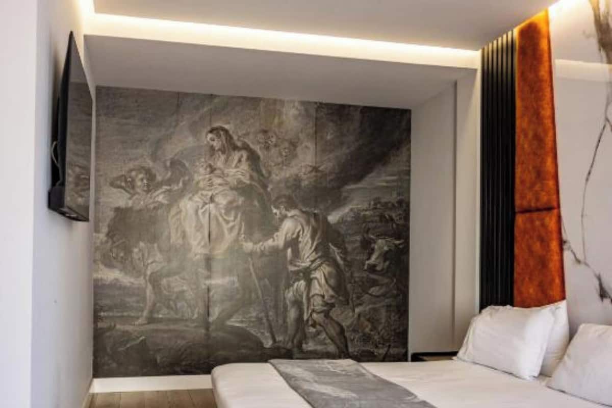 Un dormitorio moderno con una cama grande, televisor montado en la pared y un cuadro de gran tamaño.