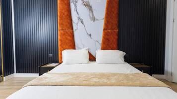 Un dormitorio moderno con una cama grande, dos mesitas de noche y una pared de acento de mármol.