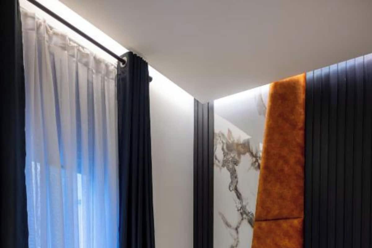 Un dormitorio moderno con cama, mesita de noche y ventana con cortinas.