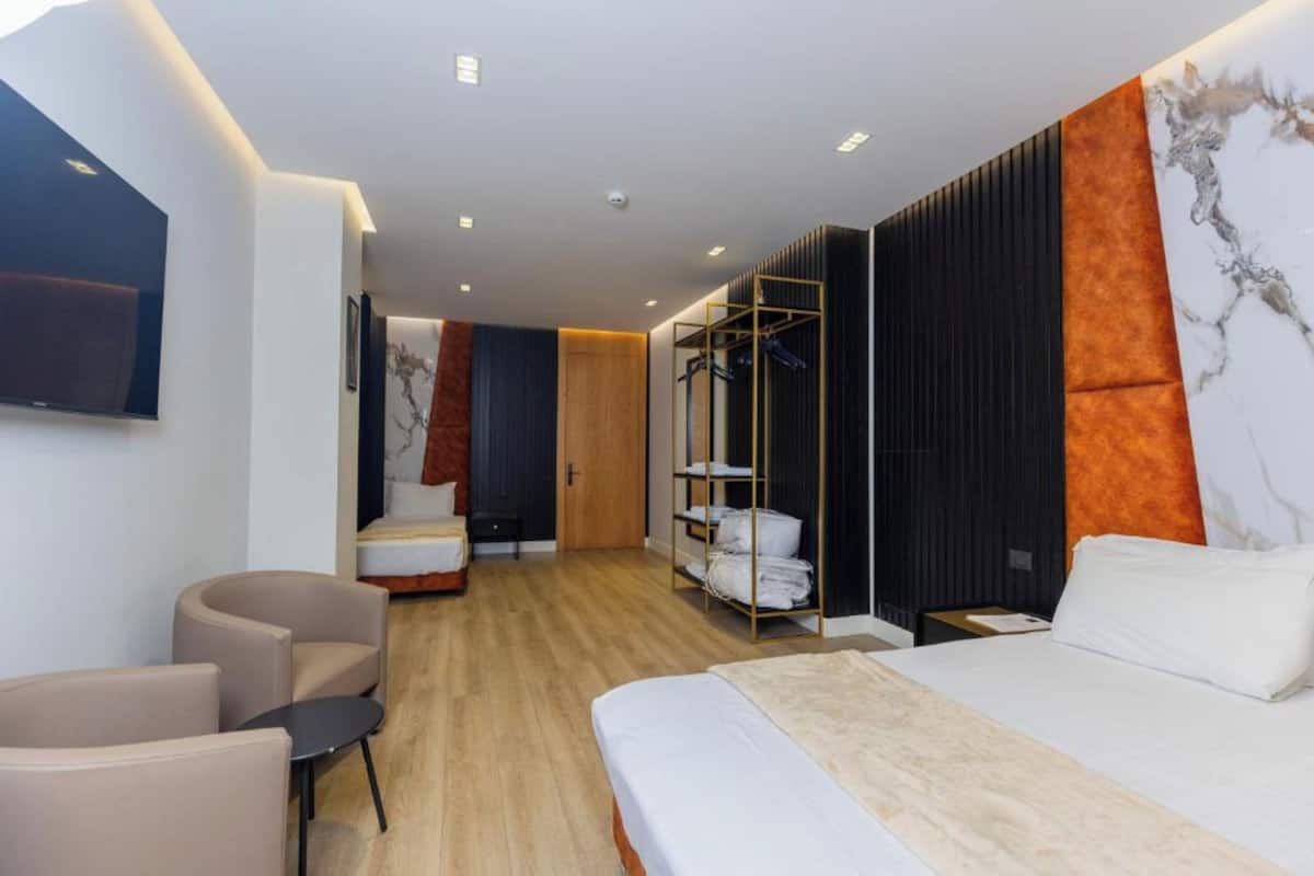 Una habitación de hotel moderna con cama, zona de estar, armario y televisor.