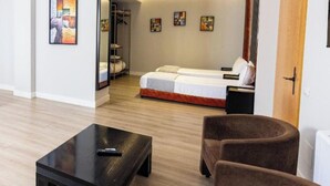 Een moderne hotelkamer met een groot bed, een zithoek met een tafel en kunstwerken aan de wanden.