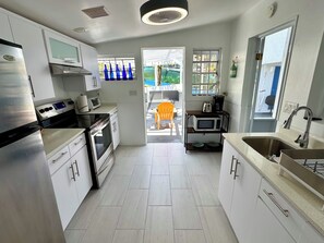 A modern kitchen with stainless steel appliances, a microwave on a shelf, and a view of the outdoor area. - Beautiful ocean view 4-bedroom house with AC in the island of Culebra PR (Culebra)