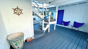 A wooden deck with a blue railing, a white door, and a blue chair. - Beautiful ocean view 4-bedroom house with AC in the island of Culebra PR (Culebra)