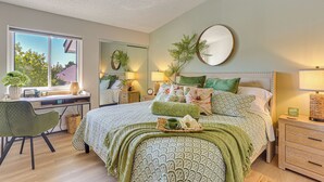 A bedroom with a bed, bedside tables, a desk, a chair, and a window.