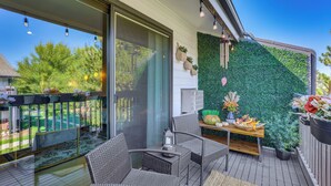 A balcony with wicker furniture, a table with decorative items, and a green wall.
