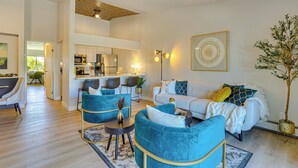 A modern living room with a sofa, two armchairs, a coffee table, and a dining area in the background.