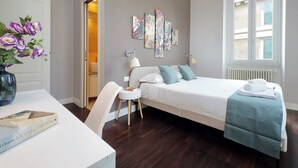 A bedroom with a bed, bedside table, lamp, and artwork on the wall. - 4BNB - Armot House Vatican Apartment (Rome)