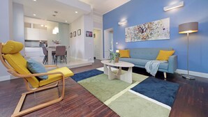 A modern living room with a yellow rocking chair, a blue sofa, and a coffee table. - 4BNB - Armot House Vatican Apartment (Rome)