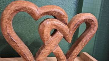 A wooden heart-shaped object with a textured surface, placed on a wooden surface against a green wall.