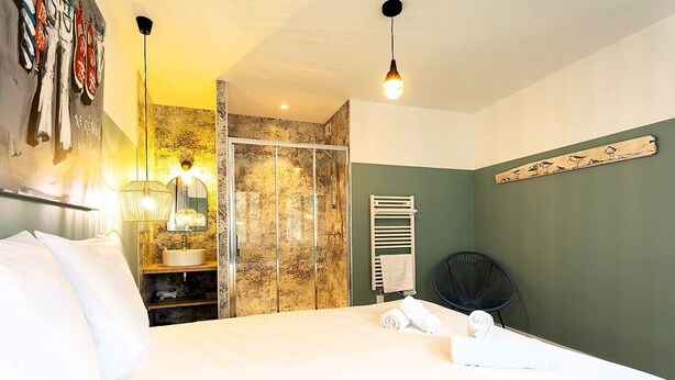 Une chambre d’hôtel comprenant un lit, une salle de bain avec douche, un porte-serviettes et une chaise.