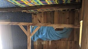 A wooden bunk bed with a patterned mattress and a blue curtain. - cocobeach chez antoine avepozo (Lomé)