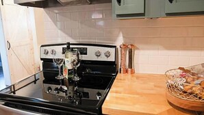 Une cuisine dotée d’appareils électroménagers en acier inoxydable, d’un plan de travail en bois et de meubles de couleur turquoise.