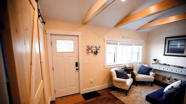 Un salon chaleureux avec une porte en bois, une cheminée et une grande fenêtre.