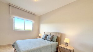 A bedroom with a bed, bedside tables, and a window.