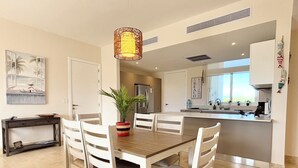 A modern kitchen with a central island, white cabinetry, and a hanging pendant light.