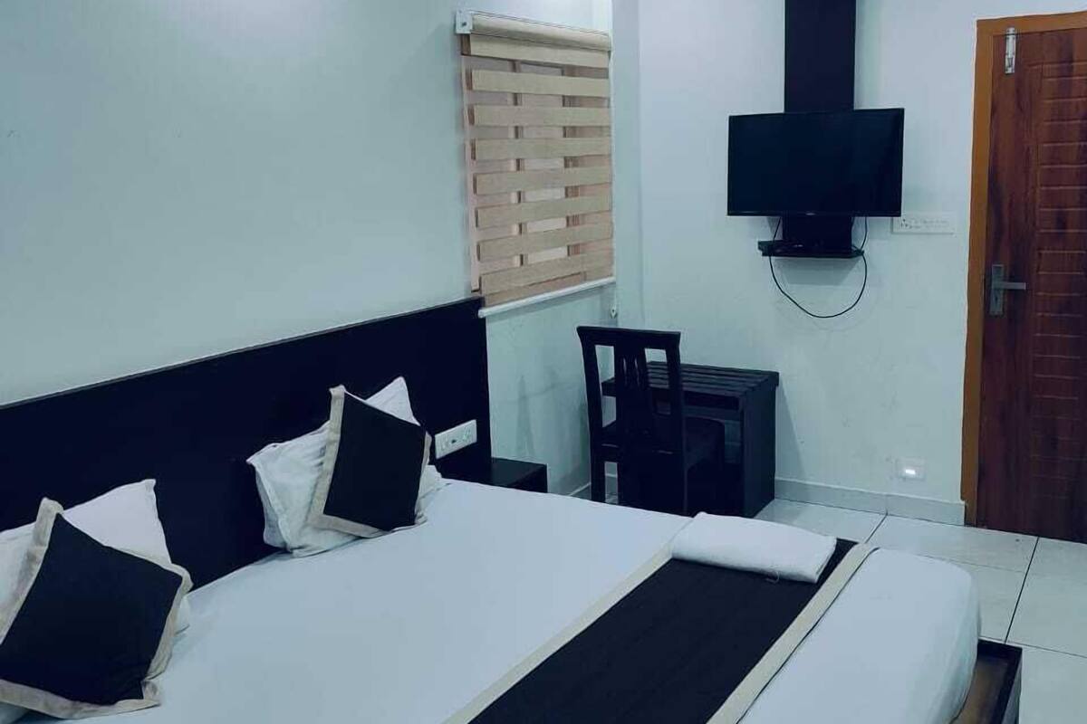 Un dormitorio con una cama grande, un ventilador de techo, un televisor montado en la pared y una puerta de madera.
