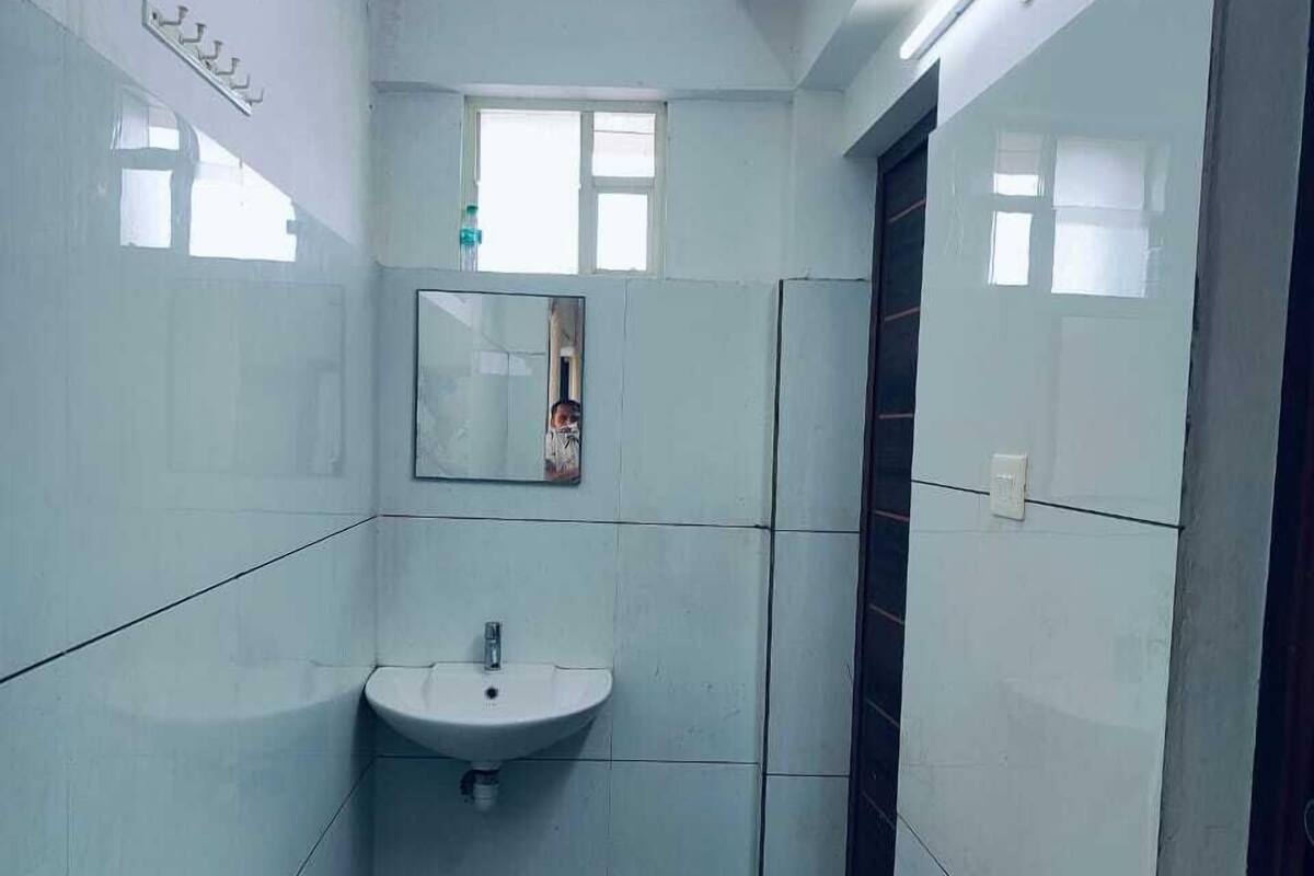 Un baño estrecho con azulejos blancos, un lavabo, una ventana pequeña y un espejo.
