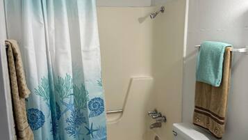 Un baño con cortina de ducha, inodoro y bañera.