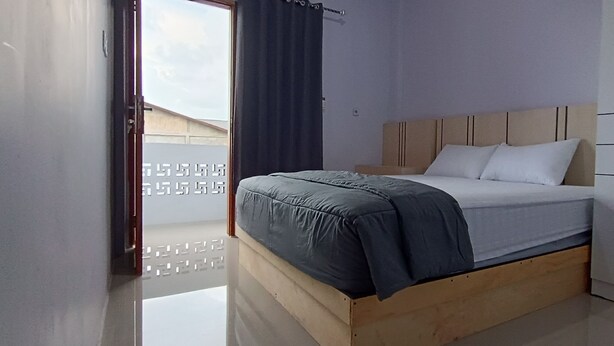A bedroom with a bed, wooden headboard, and a wardrobe.