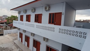 A multi-story building with red doors and air conditioning units.