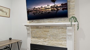A fireplace with a stone facade, a flat-screen TV mounted above it, and a framed picture on the wall to the left.