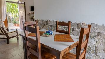 Un'area pranzo con parete in pietra, sedie di legno, tavolo bianco e un elemento decorativo al centro.