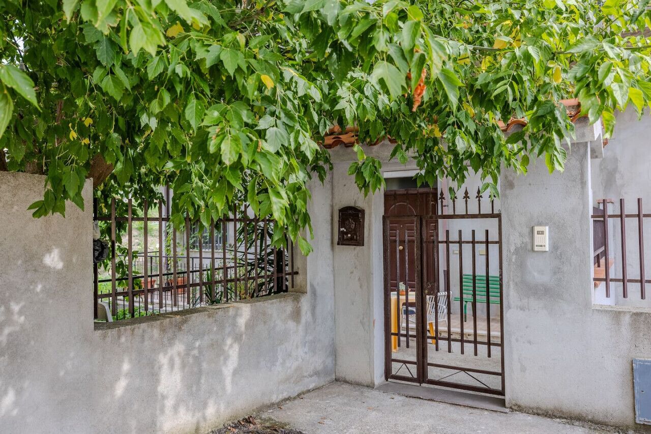 Un cancello chiuso con una porta in metallo, un muro in cemento e una piccola finestra.