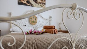 A neatly made bed with a quilted cover, a decorative pillow, and a rolled towel.