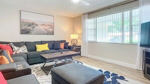 A modern living room with a sectional sofa, a coffee table, and a television.