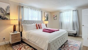 A neatly arranged bedroom with a bed, bedside tables, a bedside lamp, and a rug.