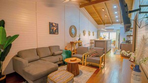 A modern living room with a sectional sofa, a coffee table, and a dining area with a bench. - Cozy House with Pool+5min walk 2 beach-Near to west bay (Roatan)