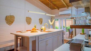 A modern kitchen with a central island, wooden ceiling beams, and a view of the outdoors. - Cozy House with Pool+5min walk 2 beach-Near to west bay (Roatan)