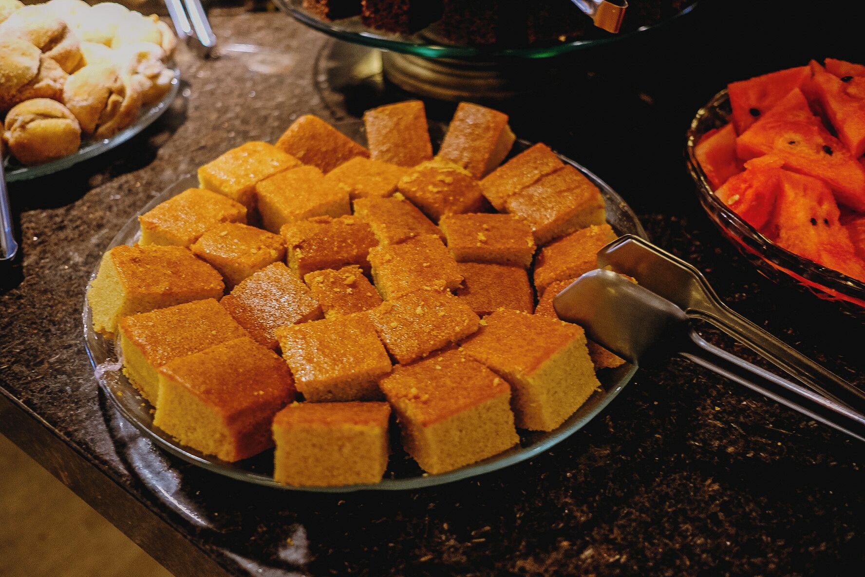 A plate of cubed food items on a glass plate with a serving utensil.