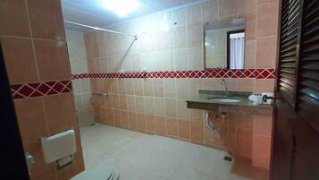 A bathroom with tiled walls, a sink, a mirror, and a shower area.