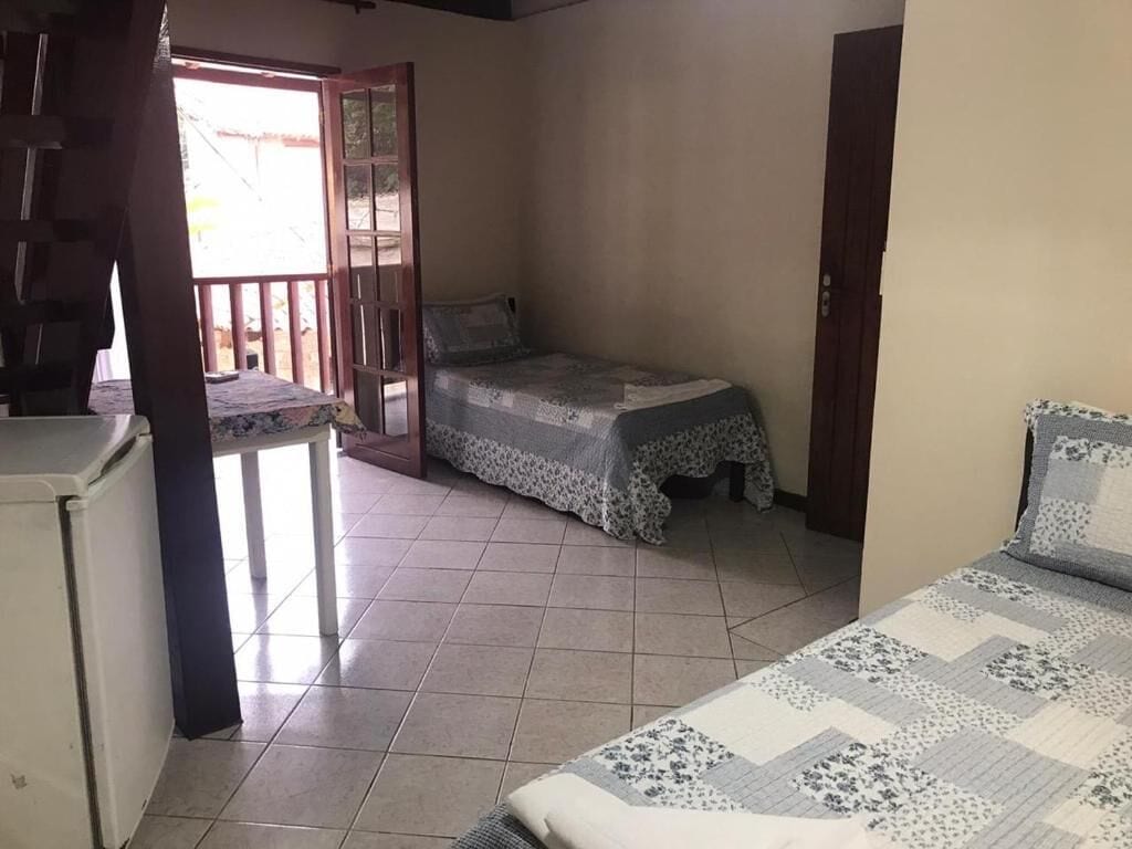 Una habitación pequeña y luminosa con cama, escritorio y balcón.