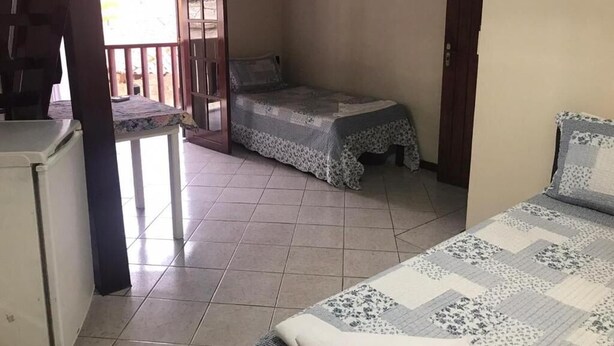 Una habitación pequeña y luminosa con cama, escritorio y balcón.