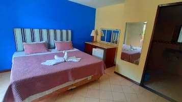 Een hotelkamer met een groot bed, een bureau, een spiegel en een schuifdeur.