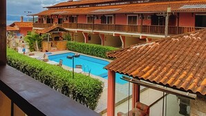 A view of a hotel with a pool, terracotta-roofed buildings, and a balcony overlooking the pool area. - POUSADA ANGRA BELLA (Angra dos Reis)