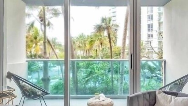 A balcony with a glass railing, two chairs, and a small round table.