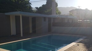 A rectangular swimming pool with a tiled edge, surrounded by a paved walkway. - MetzManor:Modern luxury Kgn retreat, scenic views,balconies,gated,self check-in  (Kingston)