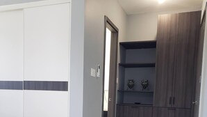 A room with a white wardrobe, a grey wall, and a wooden cabinet. - MetzManor:Modern luxury Kgn retreat, scenic views,balconies,gated,self check-in  (Kingston)