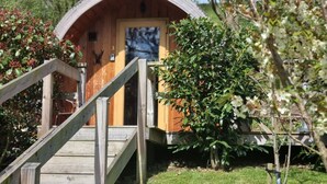 A wooden cabin with a wooden staircase leading to a door, surrounded by greenery and trees. - mega pod 3 -  a mega pod that sleeps 4 guests  in 1 bedroom (Church Stretton)