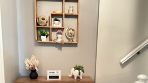 Une console en bois ornée d’un globe terrestre, de plantes en pot et d’une pancarte indiquant le mot de passe du réseau Wi-Fi.