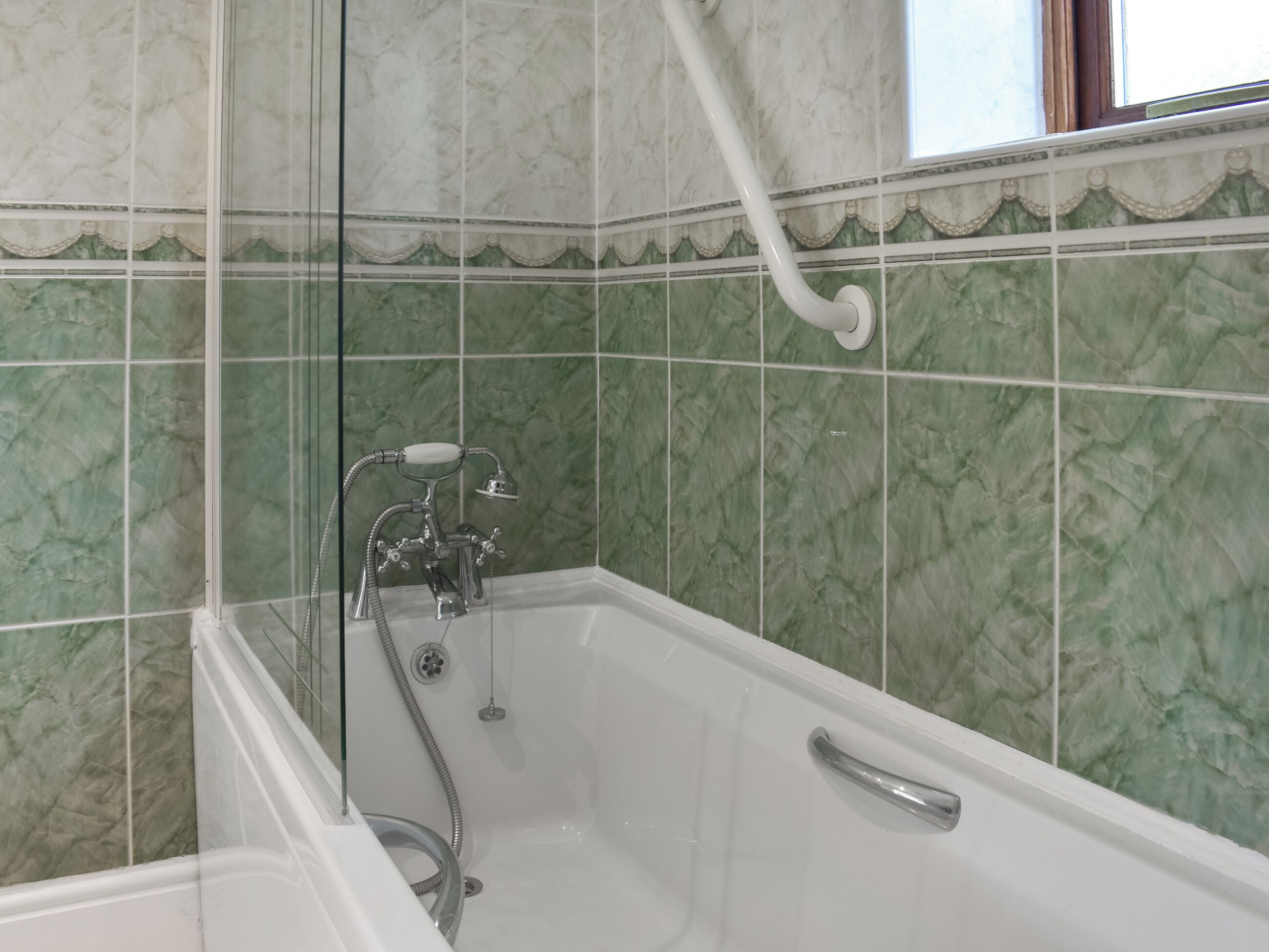 Une salle de bain avec une baignoire, une douche et des carreaux de marbre vert.