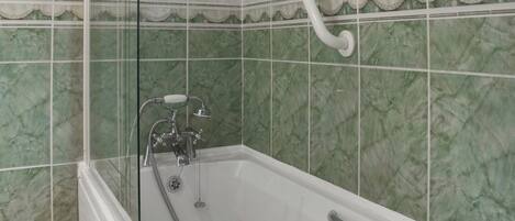 Une salle de bain avec une baignoire, une douche et des carreaux de marbre vert.