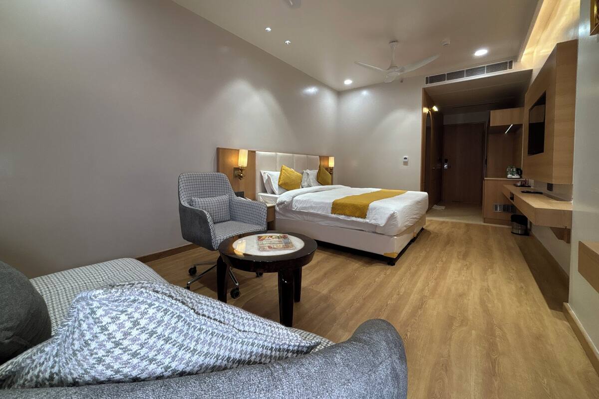 A modern hotel room with a bed, a chair, a small table, and a sofa.