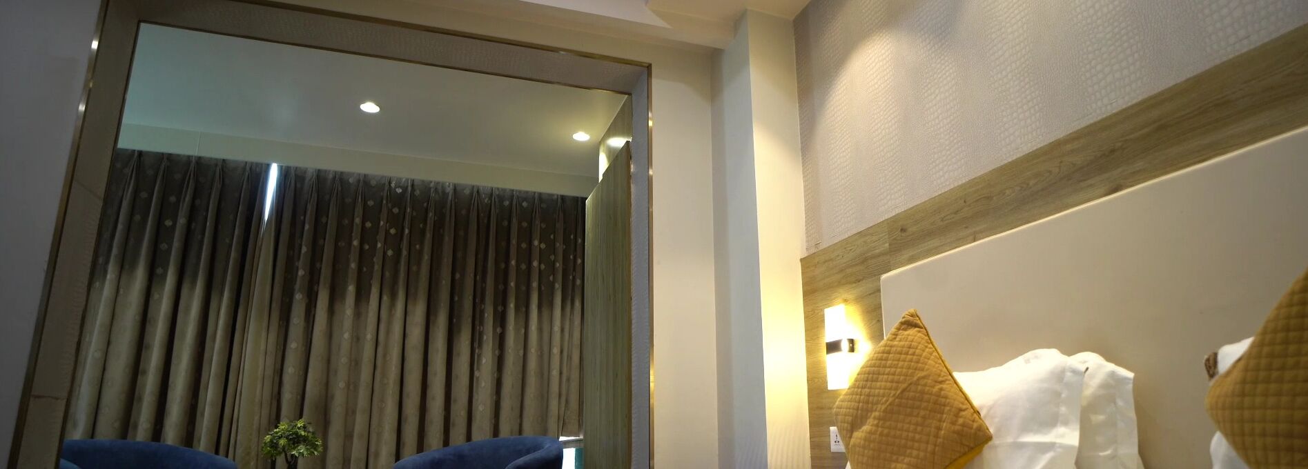 A bathroom with a large mirror, a towel rack, and a small plant.