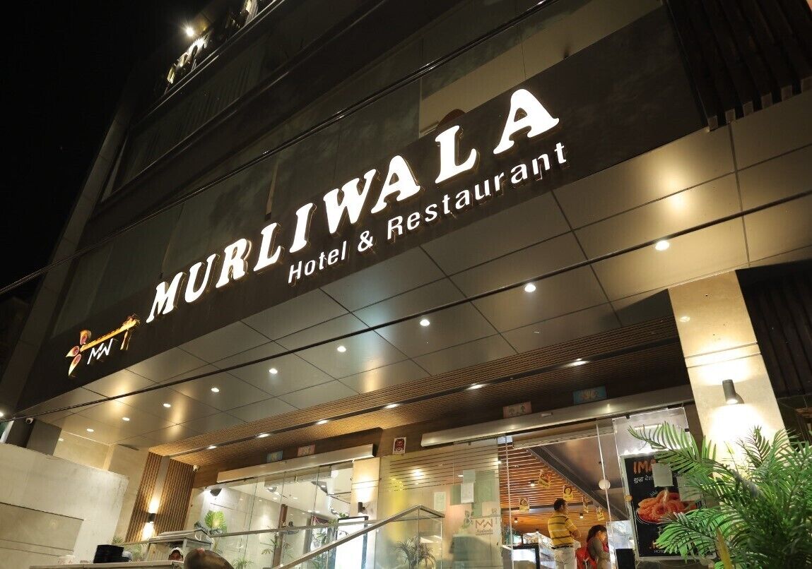 L’extérieur de l’hôtel-restaurant Murliwala, avec sa façade moderne, son entrée en verre et son enseigne bien visible.