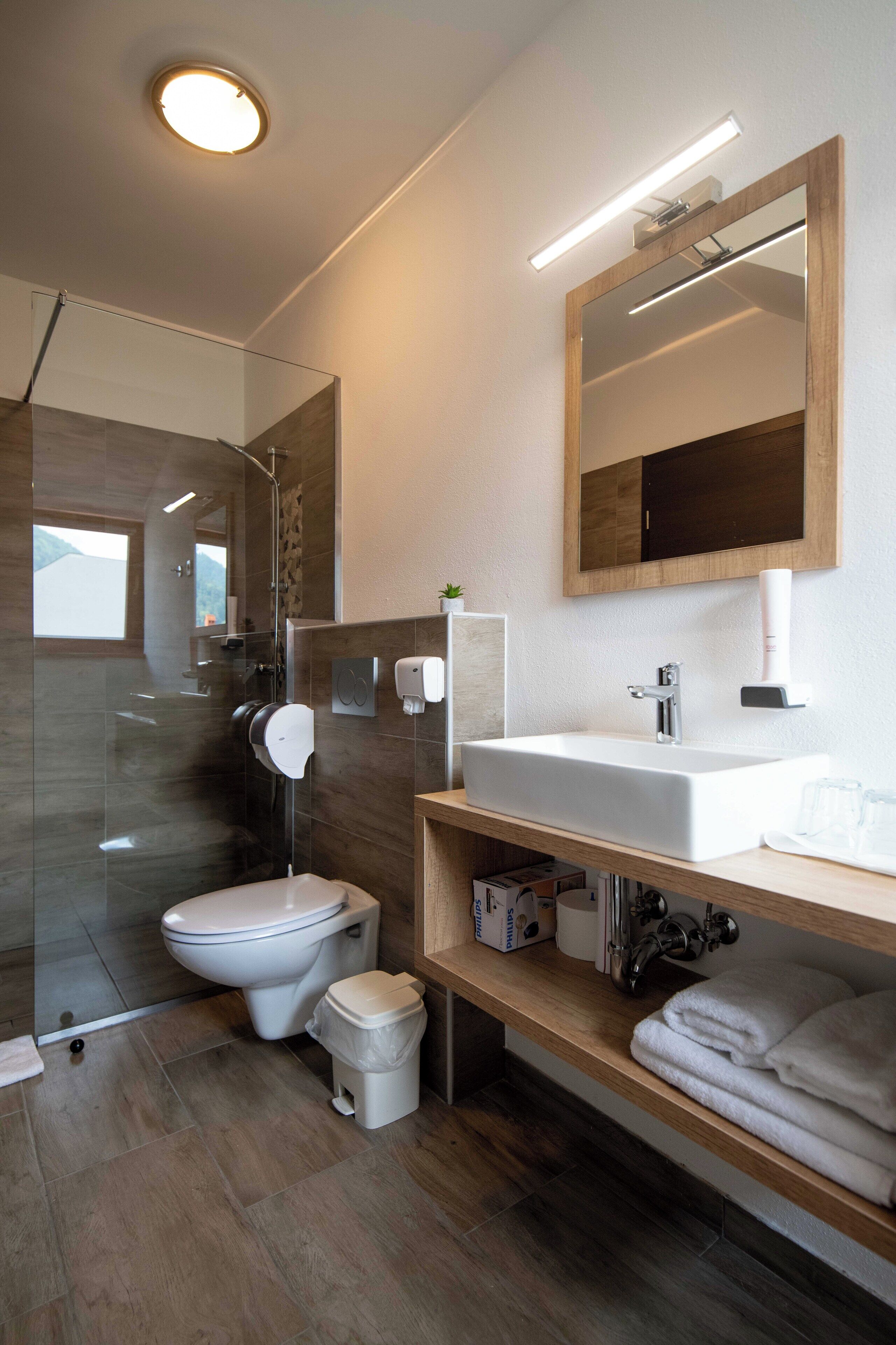 A modern bathroom with a glass shower enclosure, a white sink, and a mirror above it.