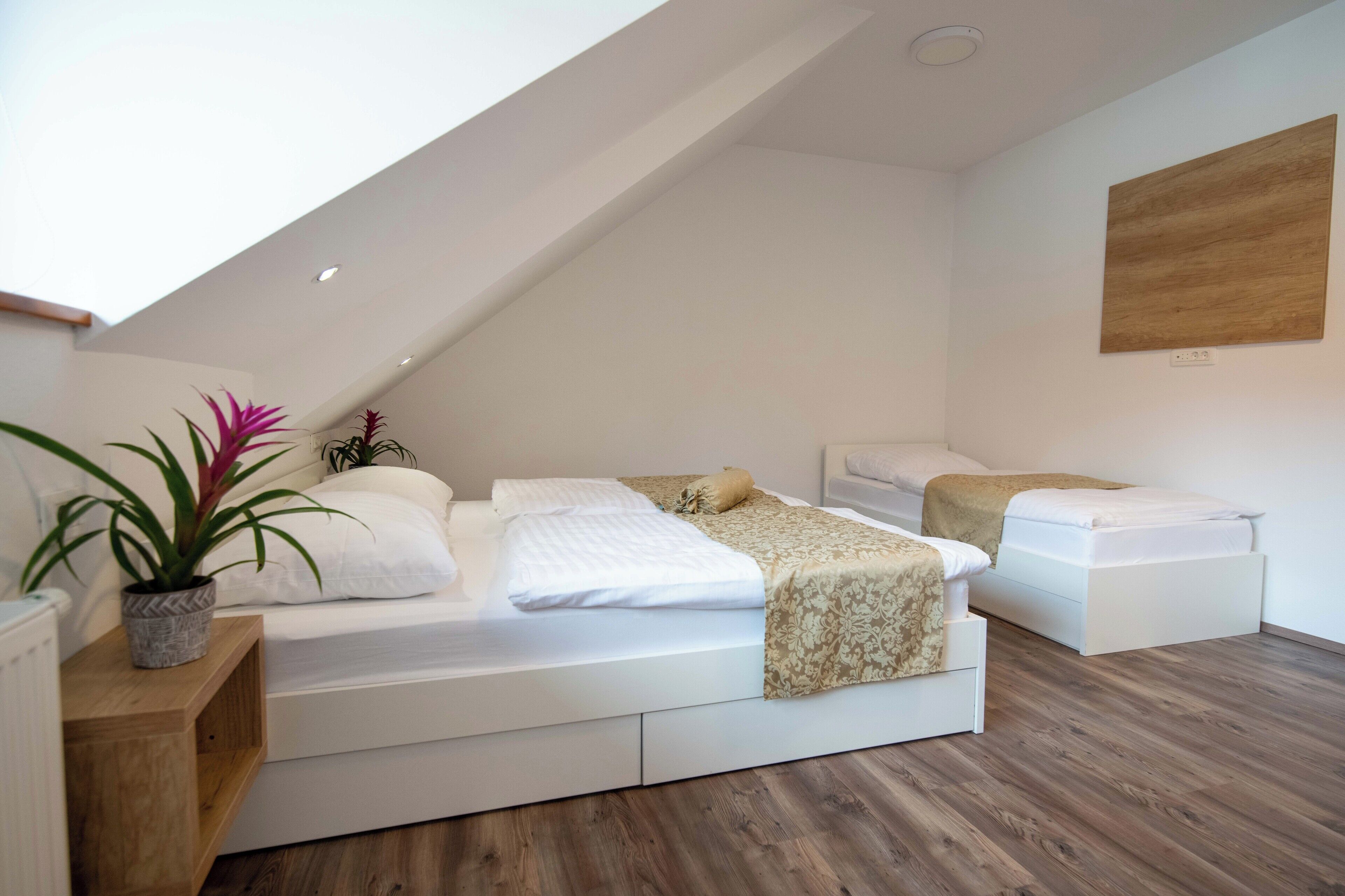 Een moderne loft slaapkamer met een schuine kap, een groot raam en een houten vloer.